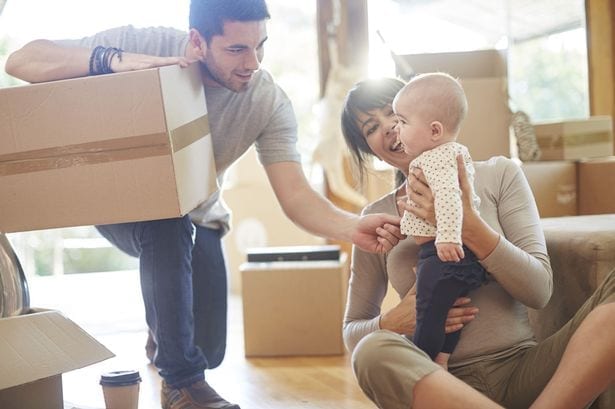 Couple with a baby moving house with movers