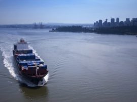 A ship carrying containers sails through a port