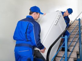 Movers carrying a fridge up stairs.